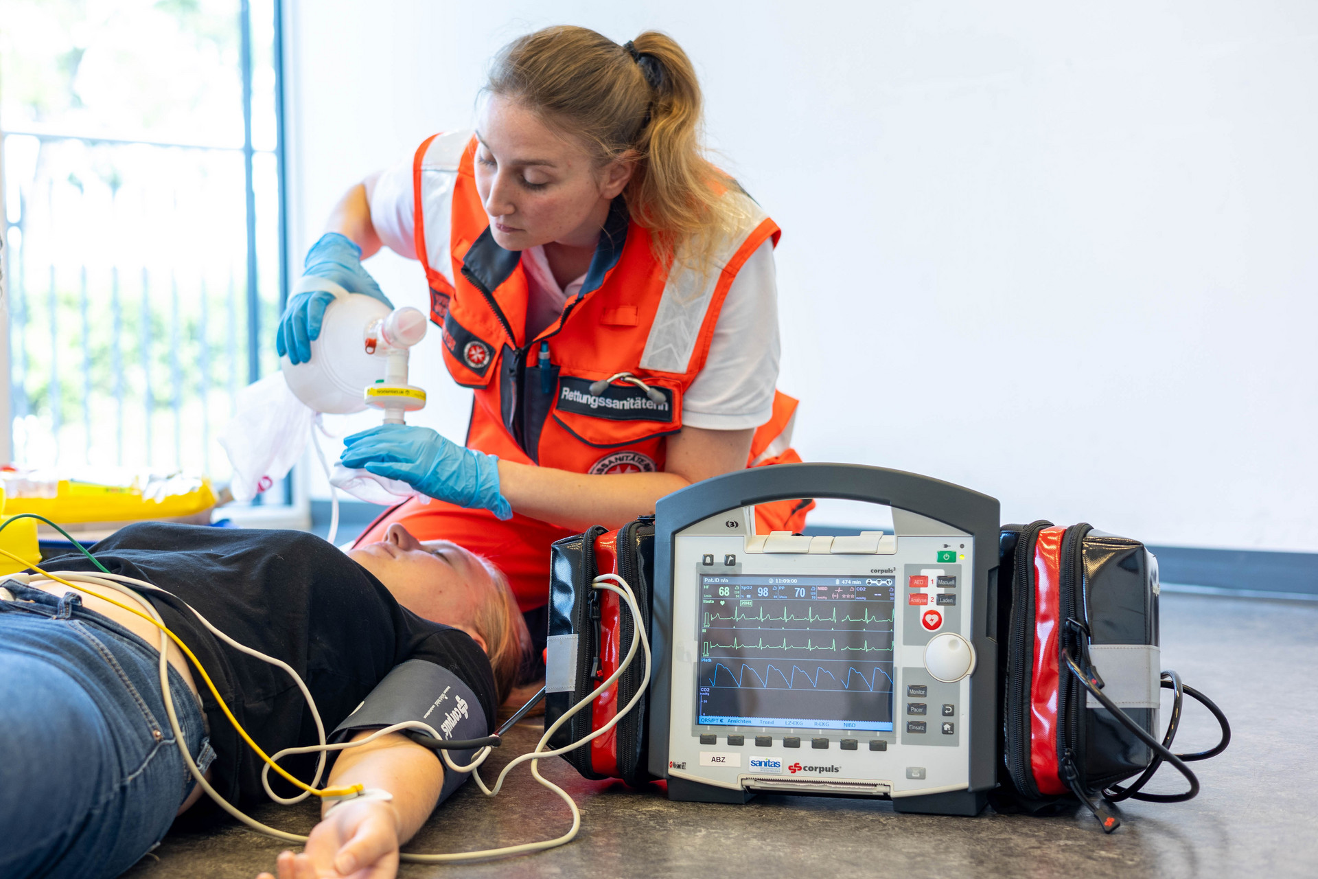 Eine Rettungssanitäterin beatmet mit einem Beatmungsbeutel. Die Patientin ist am Corpuls angeschlossen.