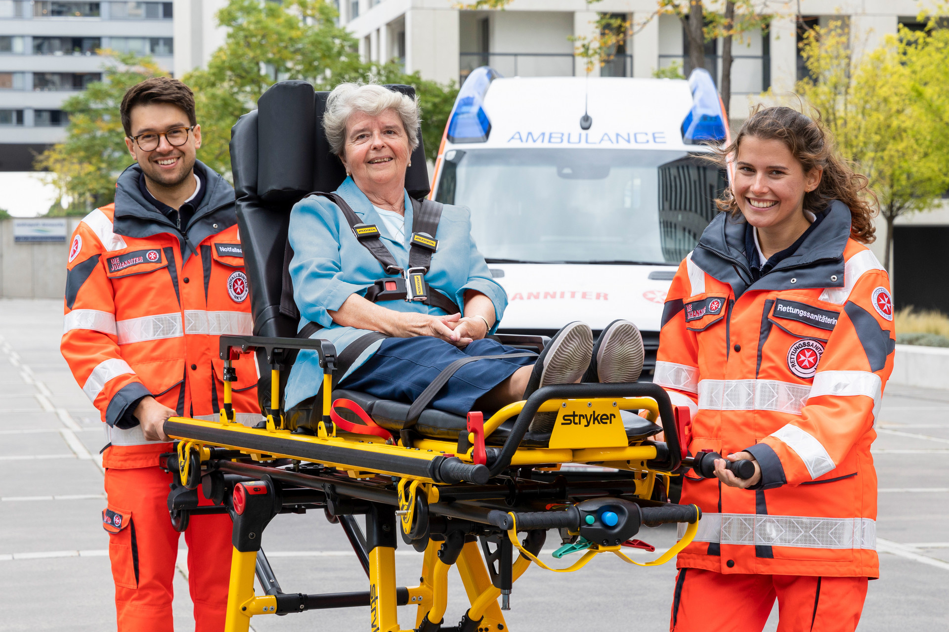 Zwei ehrenamtliche Sanitäter:innen transportieren eine Patientin auf einer Fahrtrage.