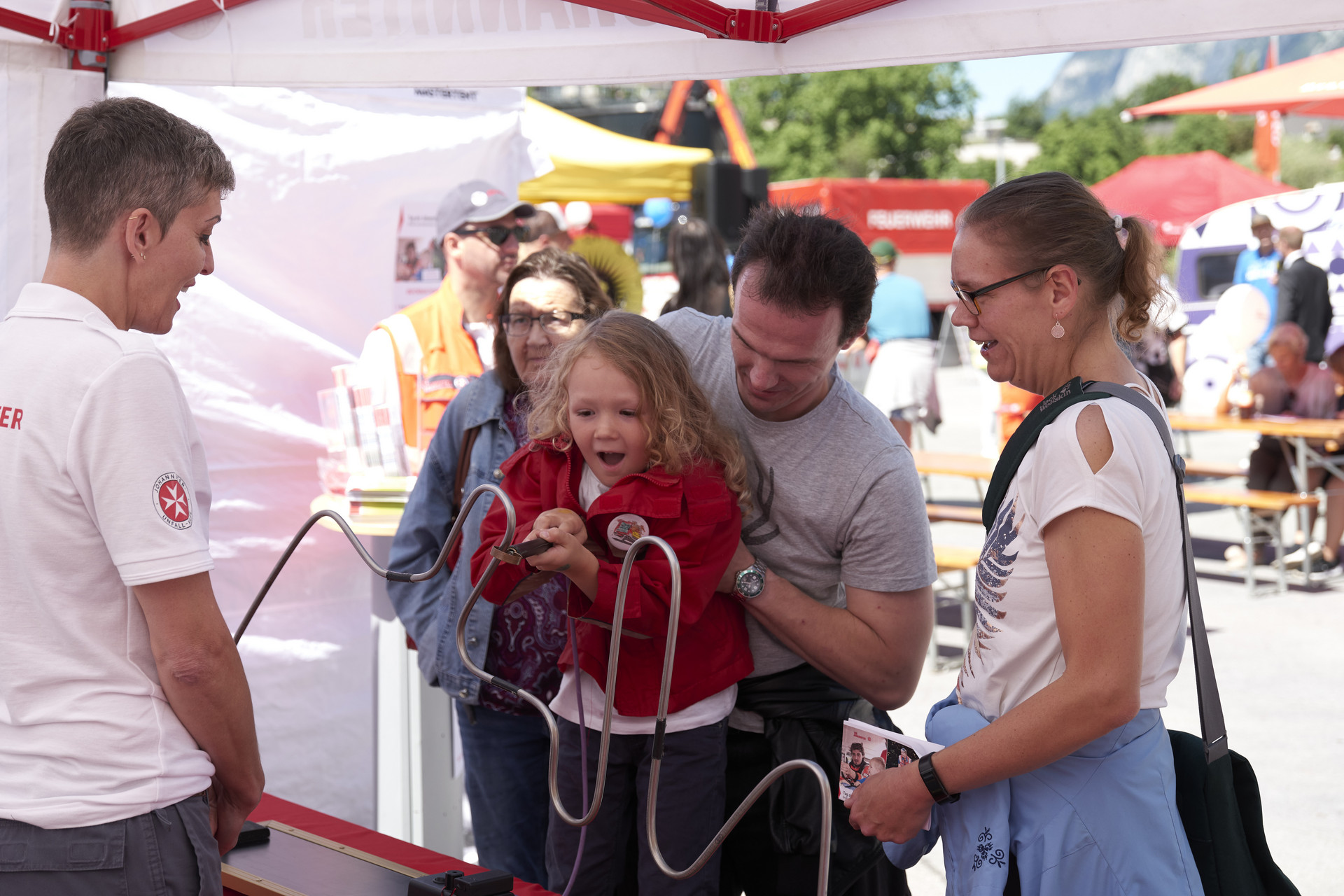 Ein Mädchen wird von ihrem Vater hochgehoben und probiert sich an einem Geschicklichkeitsspiel.