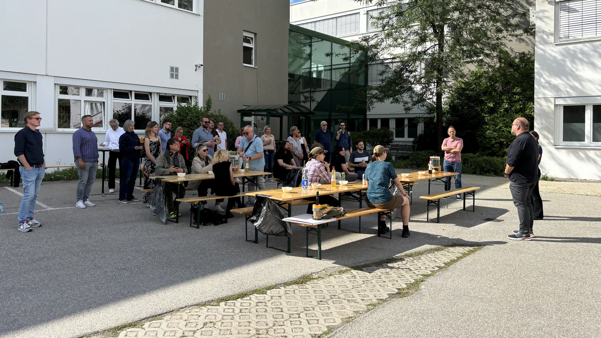 Heurigenbänke sind vor einem Haus aufgestellt. Leute essen.