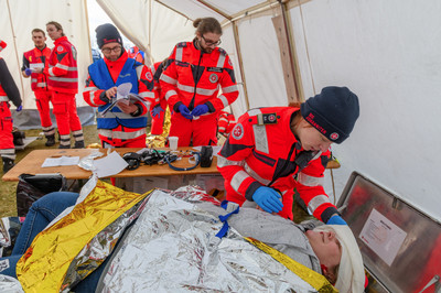Eine Sanitäterin versorgt ine Patientin, die auf einer Liege liegt.