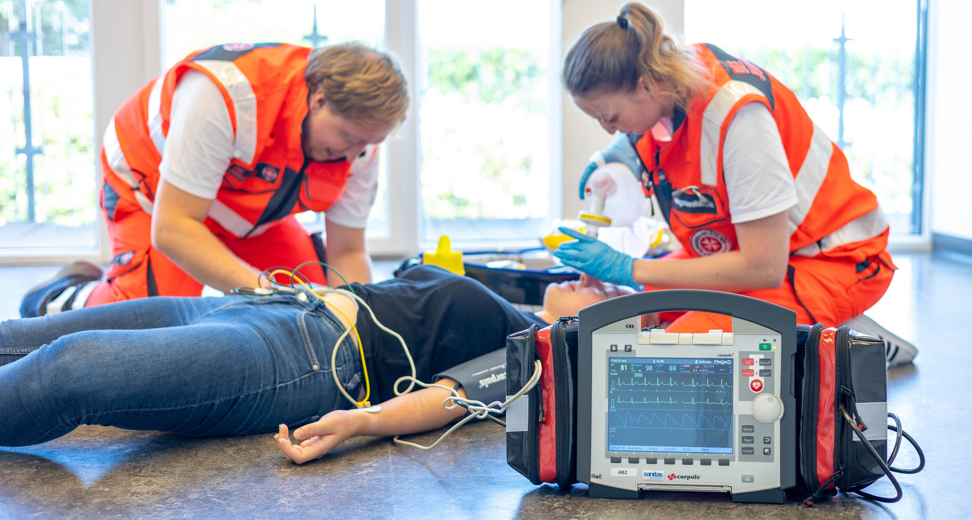 Ein Rettungssanitäter und eine Rettungssanitäterin versorgen eine Patientin mithilfe des Corpuls-Geräts.