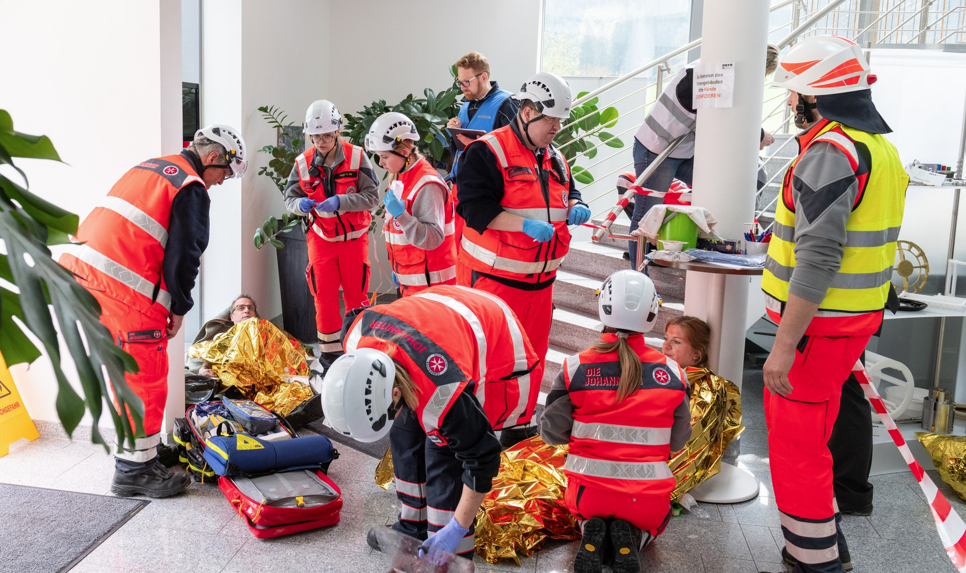 Sanitäter:innen versorgen mehrere verletzte Personen, die am Boden liegen.
