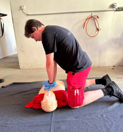 Ein Mann reanimiert an einer Reanimationspuppe.