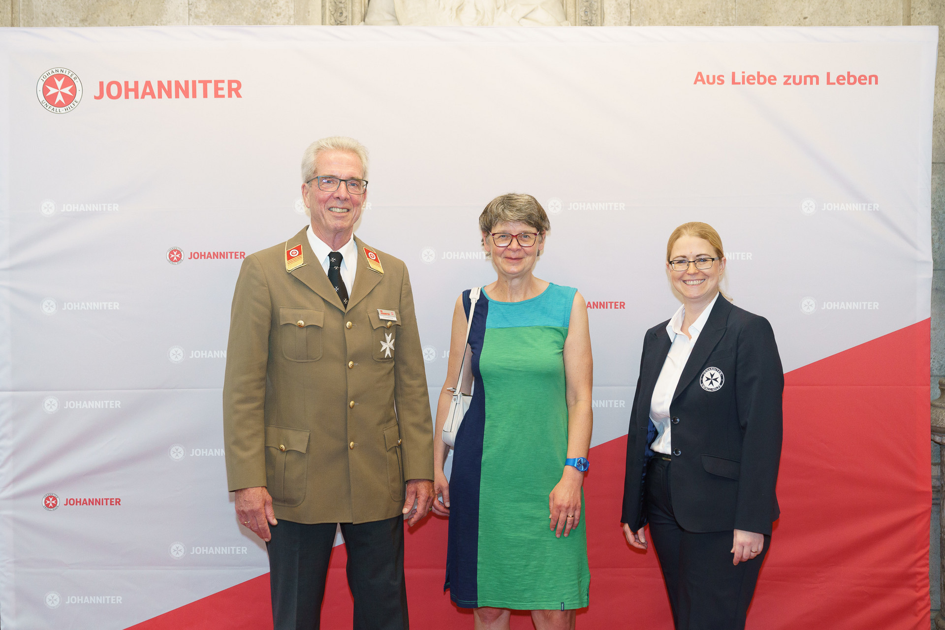 Präsident Johannes Bucher und Bundesgeschäftsführerin Petra Grell-Kunzinger mit Personen vor einer Johanniter Leinwand