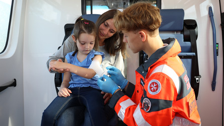 Zivildiener legt einem Kind einen Verband an.
