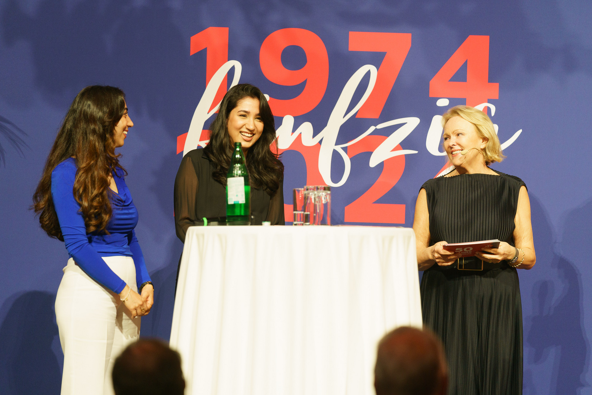 3 Damen stehen auf der Bühne und unterhalten sich