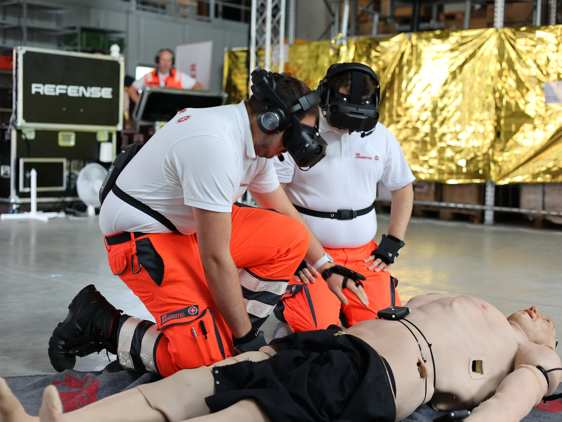 zwei Sanitäter mit VR-Brille beugen sich über eine Simulationspuppe
