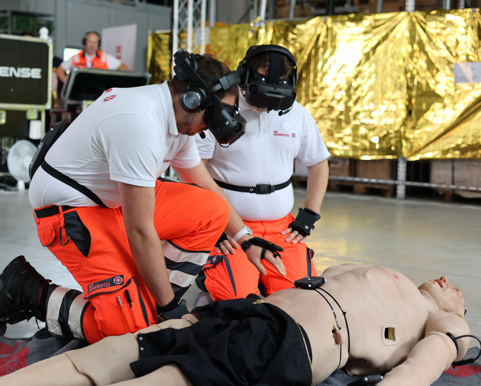 Zwei Sanitäter mit VR-Brille versorgen eine Puppe.