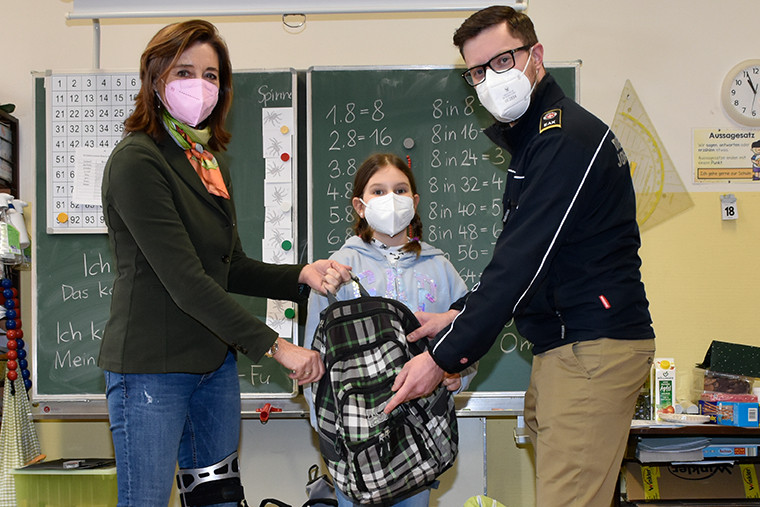 Eine Lehrerin und eine Schülerin mit einem Johanniter bei der Spendenübergabe der Volksschule Sievering