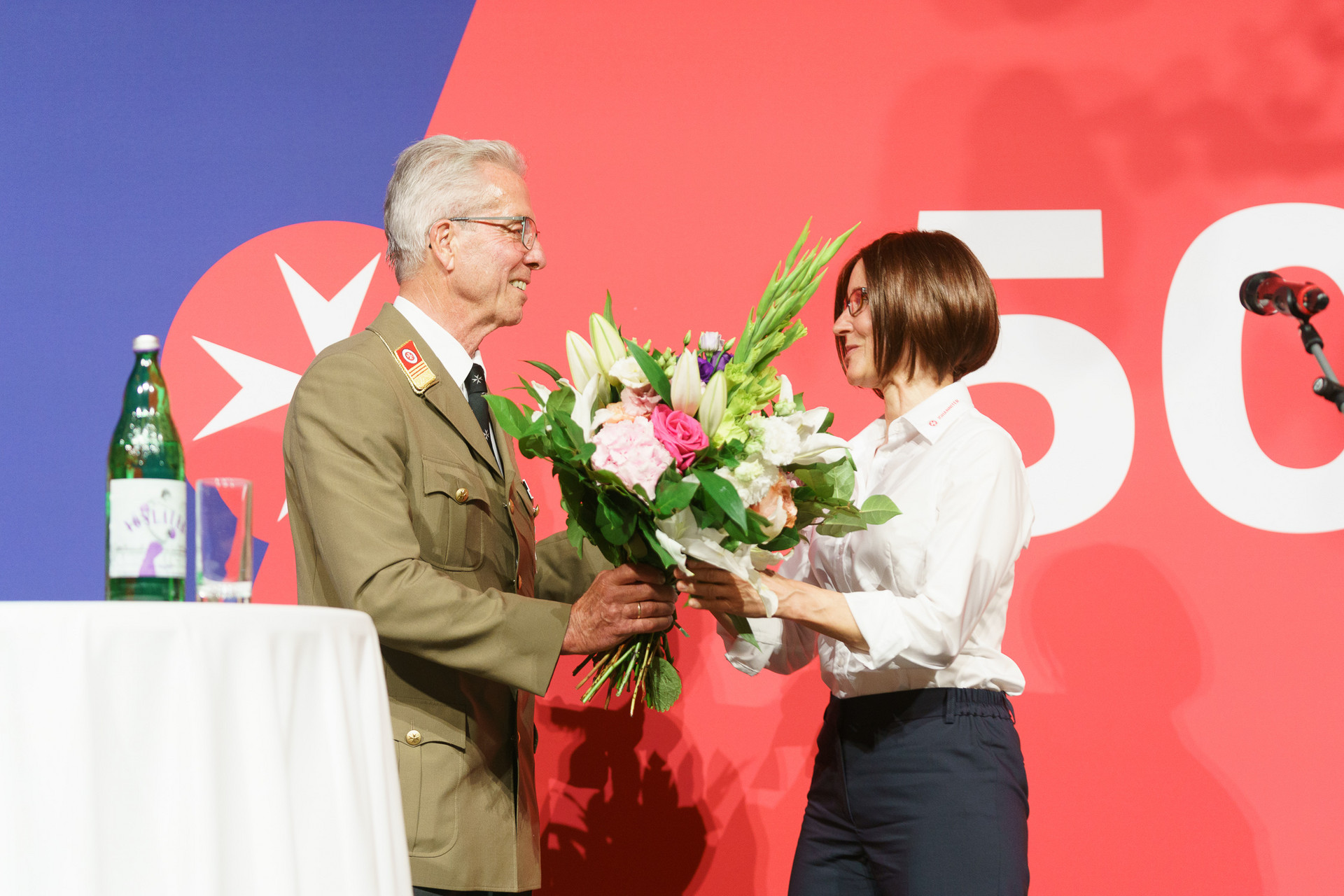 Präsident Johannes Bucher übergibt einer Frau einen Blumenstrauß