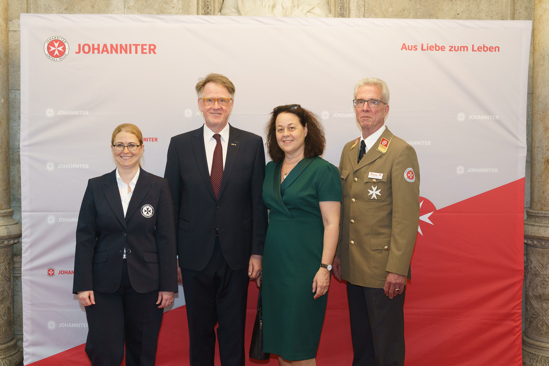 Präsident Johannes Bucher und Bundesgeschäftsführerin Petra Grell-Kunzinger mit Personen vor einer Johanniter Leinwand
