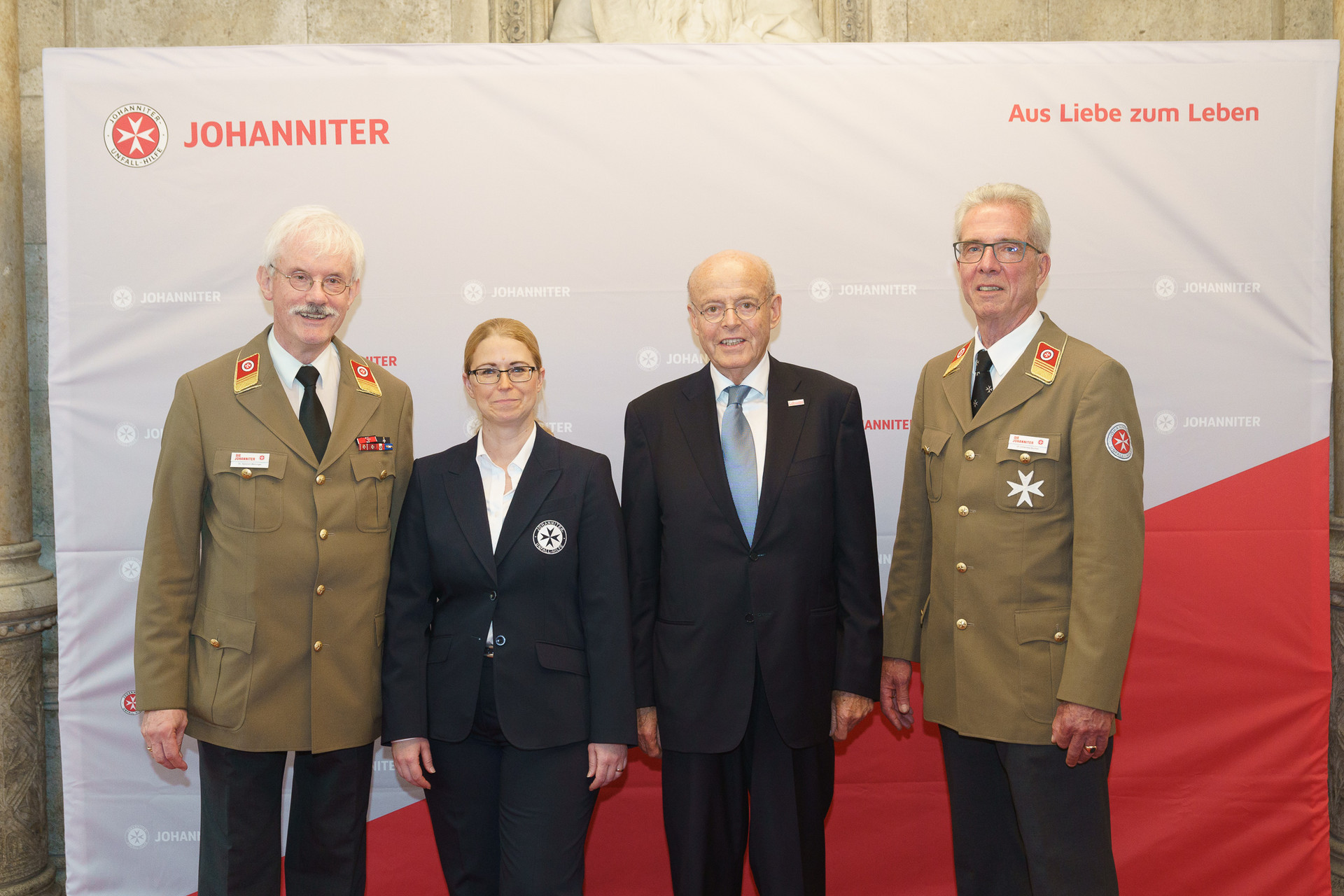 Präsident Johannes Bucher und Bundesgeschäftsführerin Petra Grell-Kunzinger mit Personen vor einer Johanniter Leinwand
