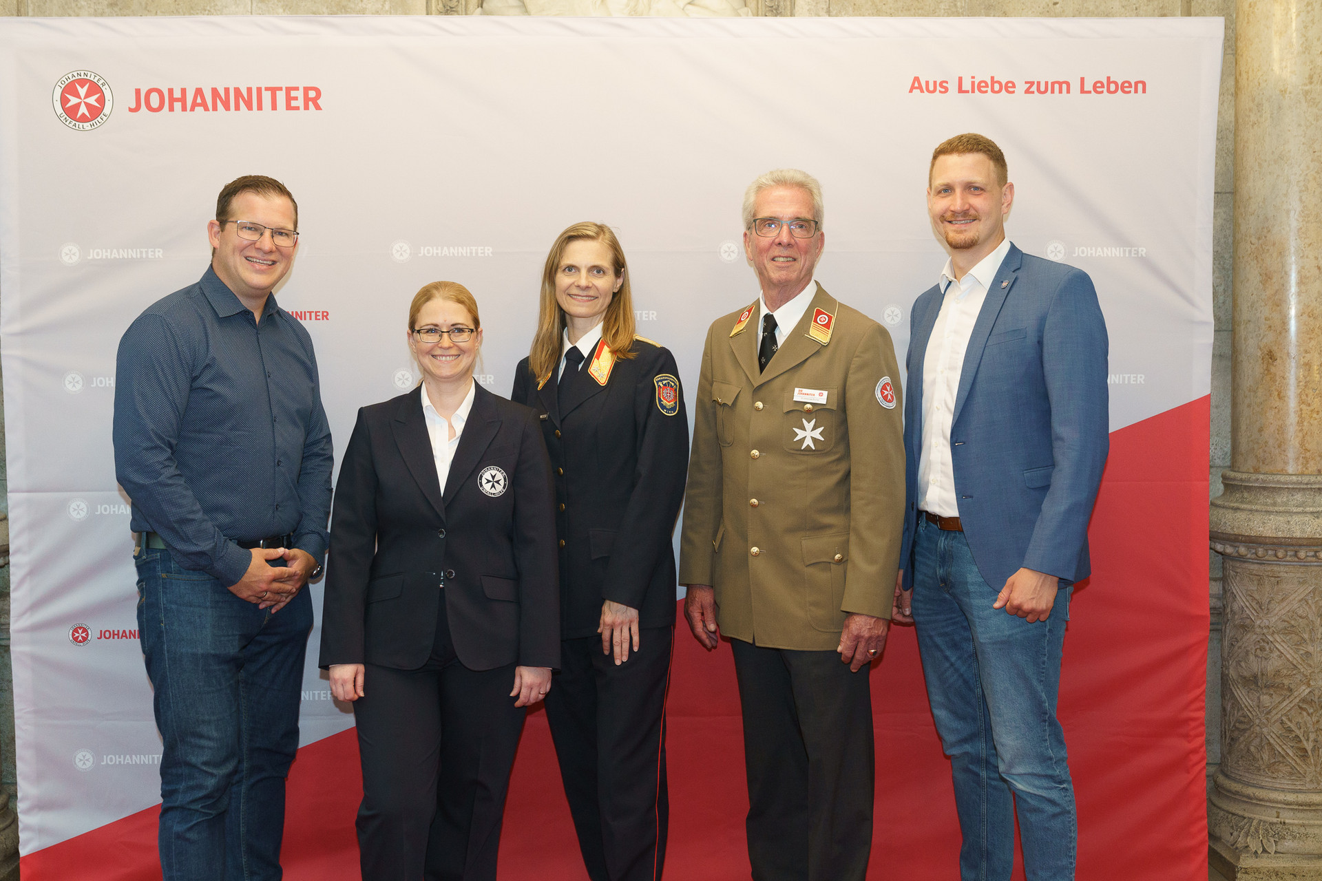 Präsident Johannes Bucher und Bundesgeschäftsführerin Petra Grell-Kunzinger mit Personen vor einer Johanniter Leinwand