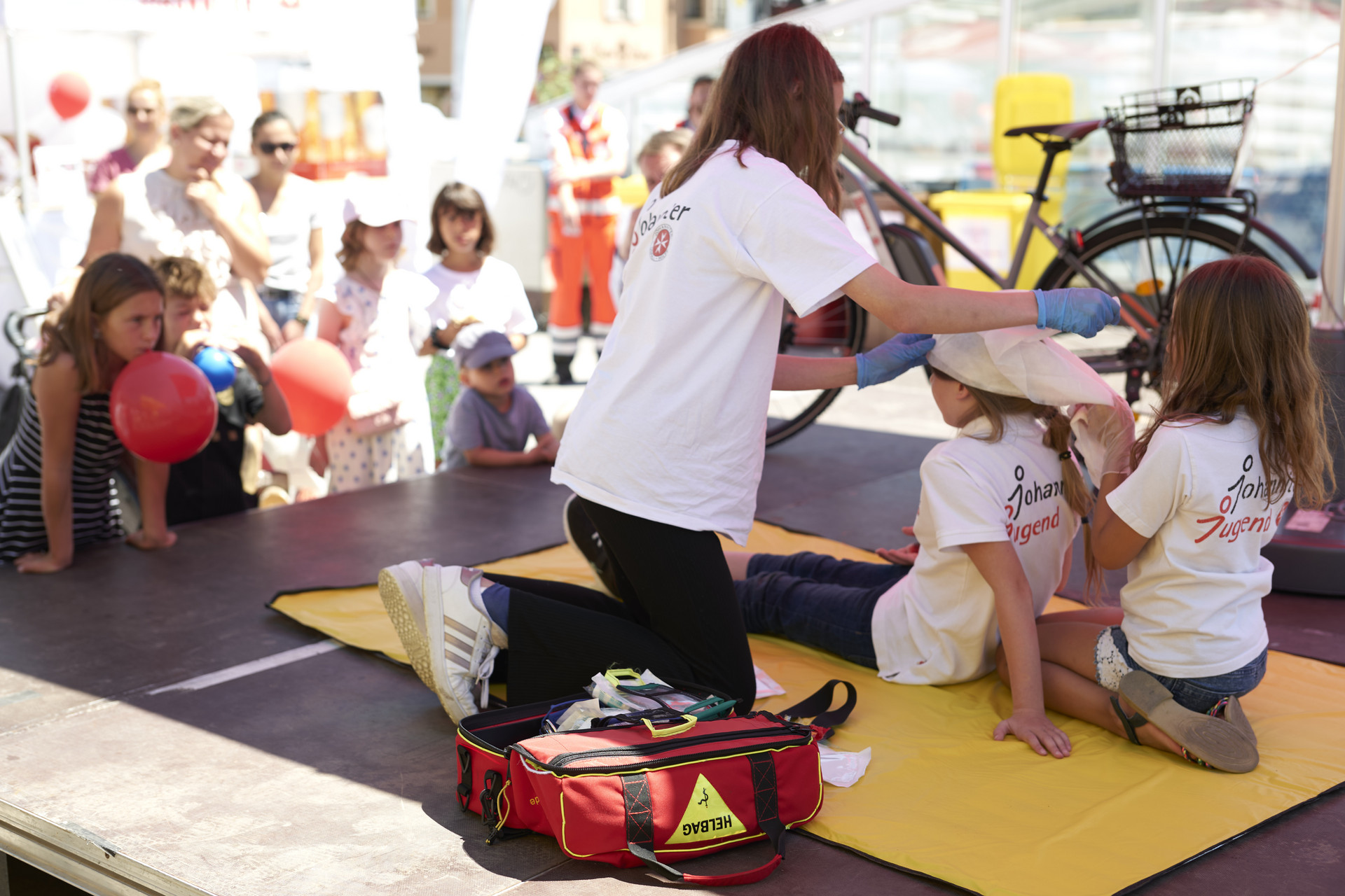 Drei Mädchen der Johanniter Jugend zeigen bei einer Erste-Hilfe-Übung das Anlegen von einem Kopfverband.