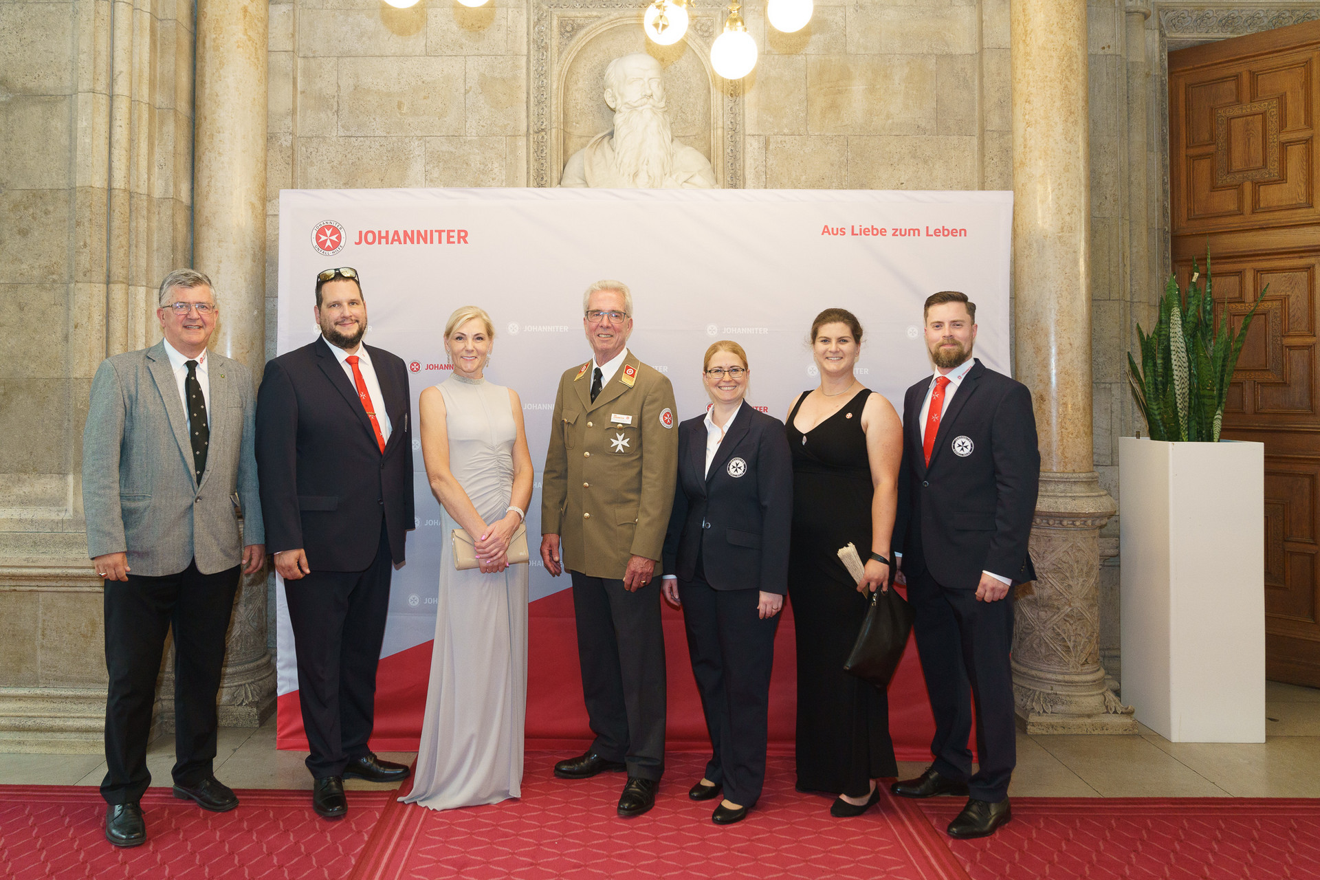 Präsident Johannes Bucher und Bundesgeschäftsführerin Petra Grell-Kunzinger mit Personen vor einer Johanniter Leinwand