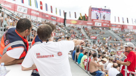 Drei Sanitäter sprechen sich im Bereich der Zuschauertribüne ab.