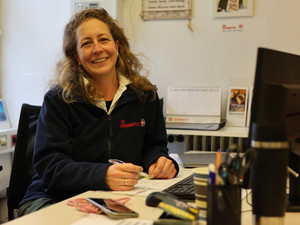 Frau sitzt lächelnd am Schreibtisch