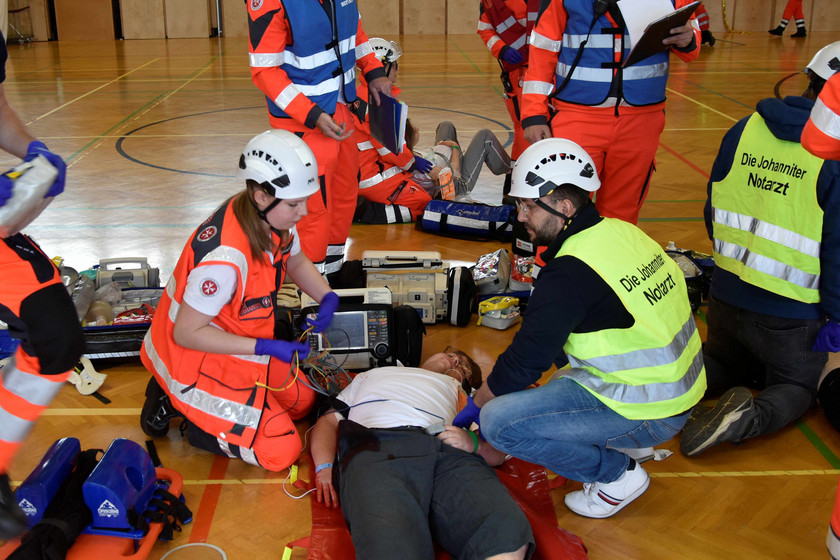 Ein Verletzter liegt am Boden und wird von Sanitäter:innen und einem Notarzt behandelt.