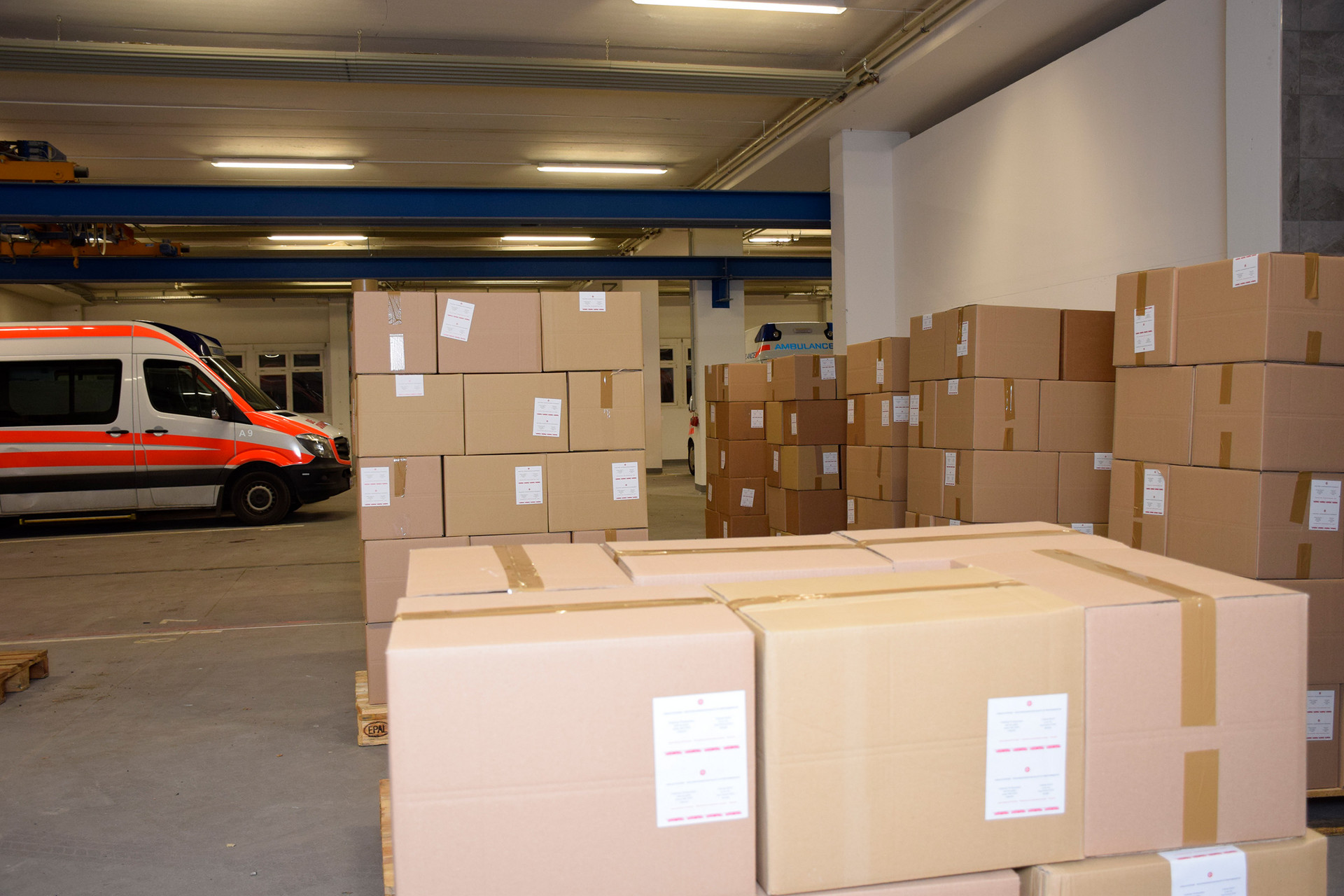 Ganz viele Hilfspakete stehen aufgestapelt auf Paletten, fertig um abgeholt zu werden.