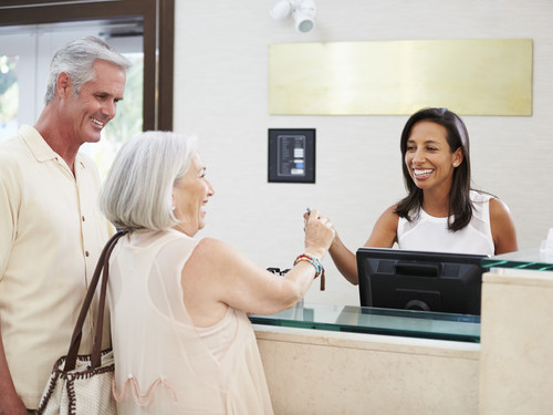 Eine Mitarbeiterin erklärt einem Seniorenpaar das Angebot.