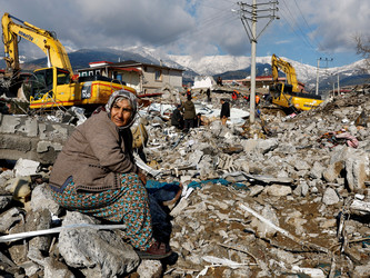 unglückliche Frau sitzt auf den Trümmern eines zerstörrten Hauses
