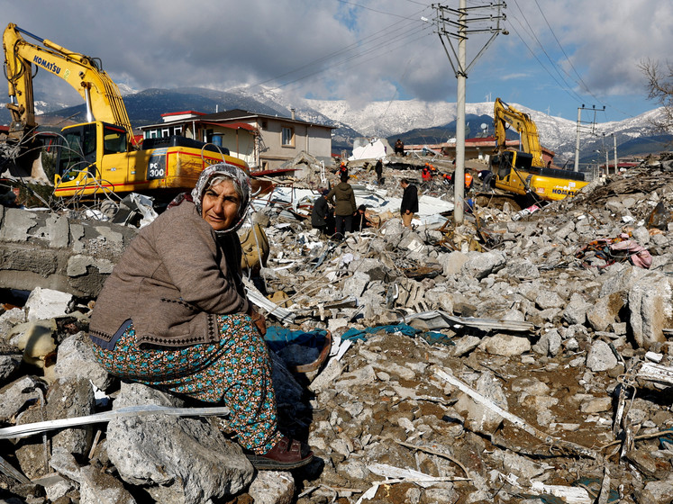 unglückliche Frau sitzt auf den Trümmern eines zerstörrten Hauses