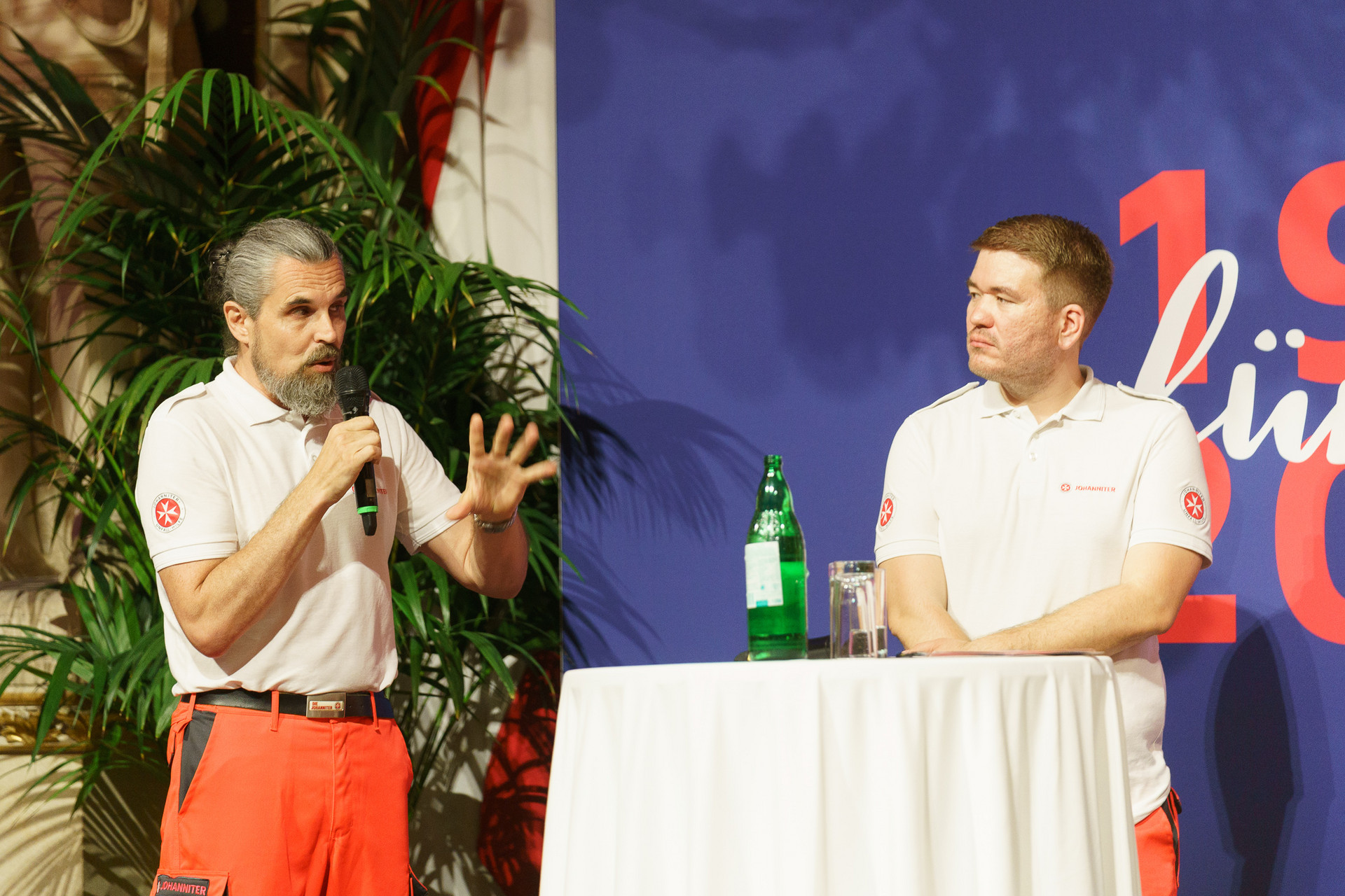 2 Personen stehen auf der Bühne und kündigen etwas an