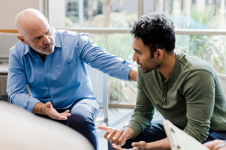 Ein älterer Mann spricht einem anderen Mann gut zu.