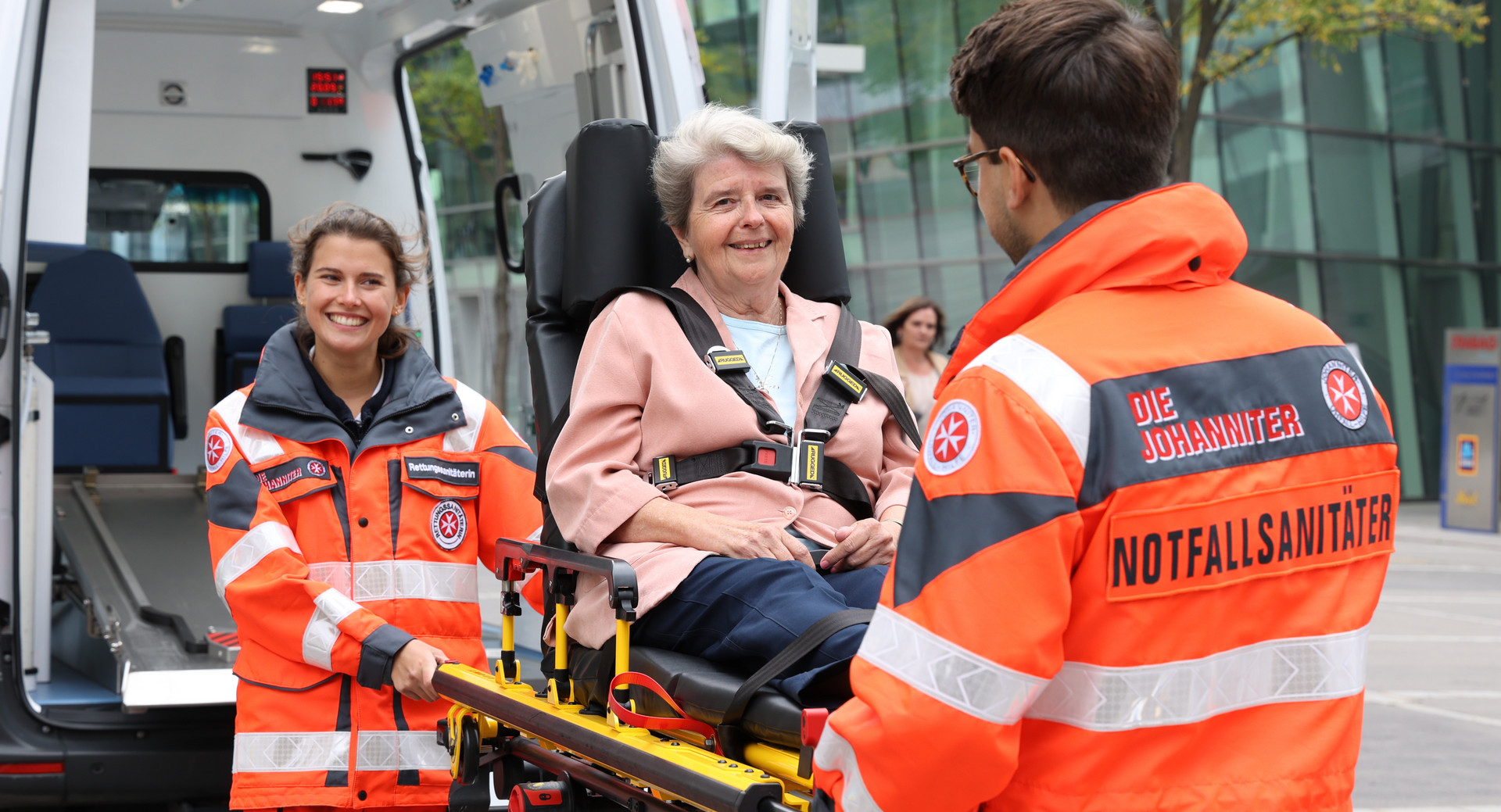 Zwei ehrenamtliche Sanitäter:innen transportieren eine Patientin auf einer Fahrtrage.