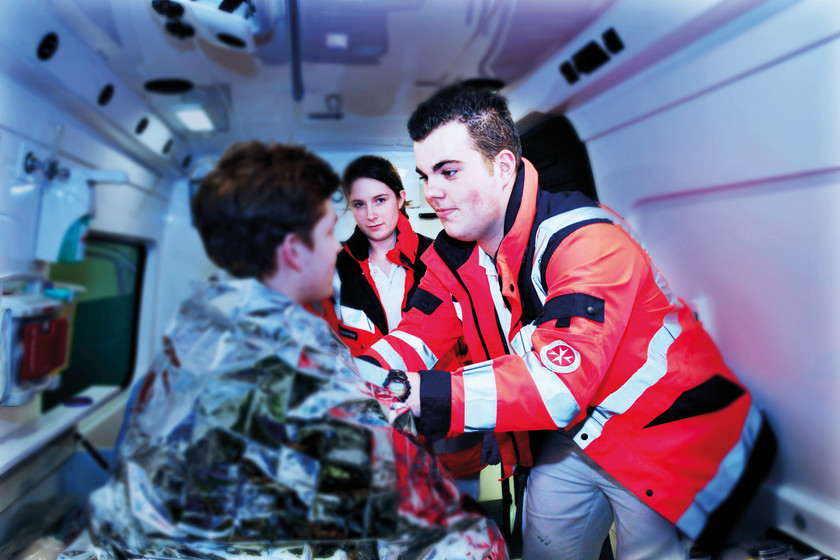 Ein Rettungssanitäter legt einem unterkühltn Patienten eine Rettungsdecke um.