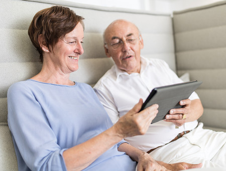 Eine Frau und ein Mann schauen auf ein Tablet, das sie in den Händen halten.