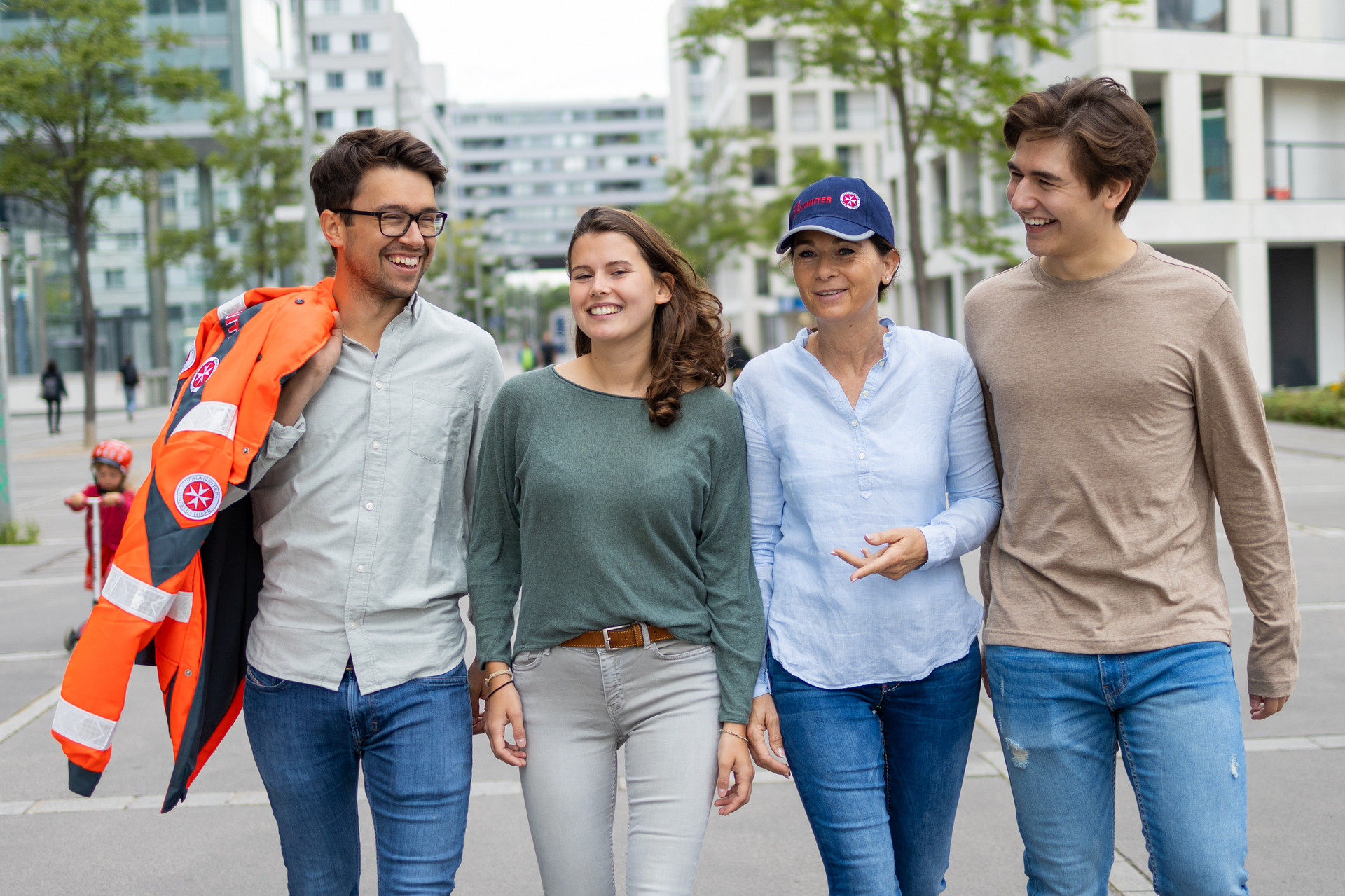 Vier Ehrenamtliche gehen nebeneinander. Einer davon trägt eine Einsatzjacke des Rettungsdienstes.