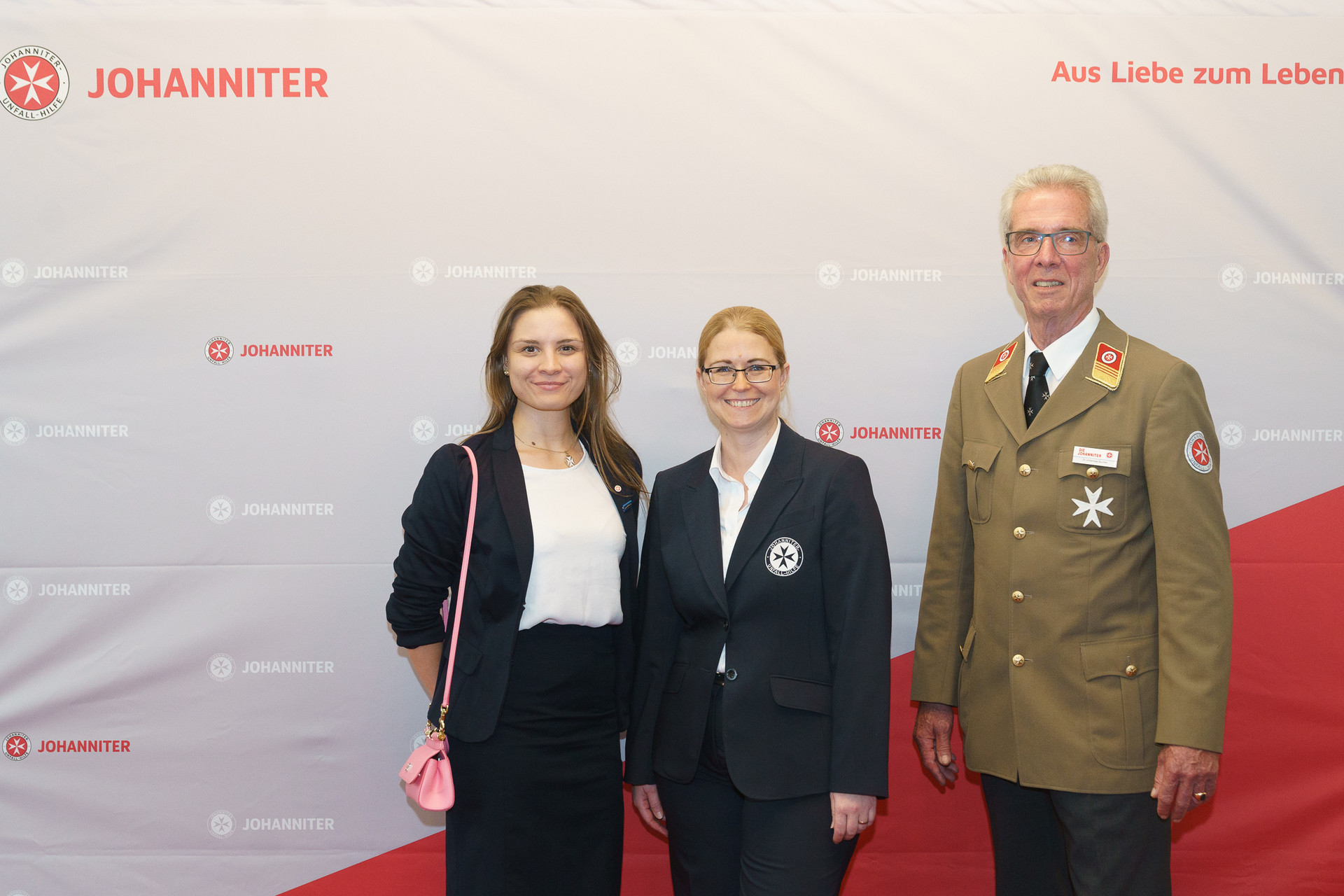 Präsident Johannes Bucher und Bundesgeschäftsführerin Petra Grell-Kunzinger mit Personen vor einer Johanniter Leinwand