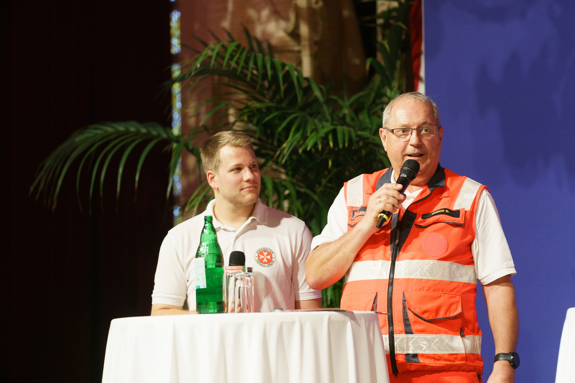 2 Personen auf der Bühne mit einer Ankündigung