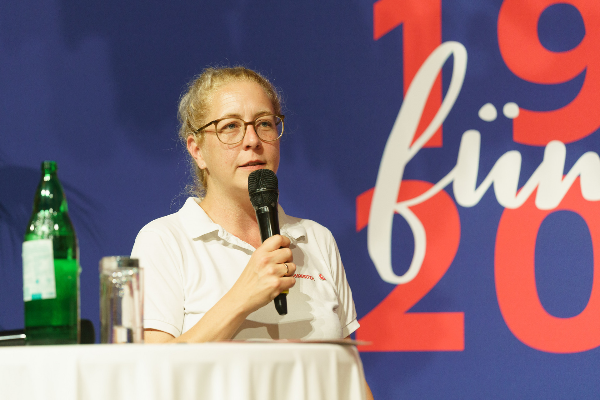 Eine Dame kündigt auf der Bühne etwas an