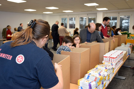 In Fließbandarbeit werden Hilfspakete mit Lebensmittel gefüllt.