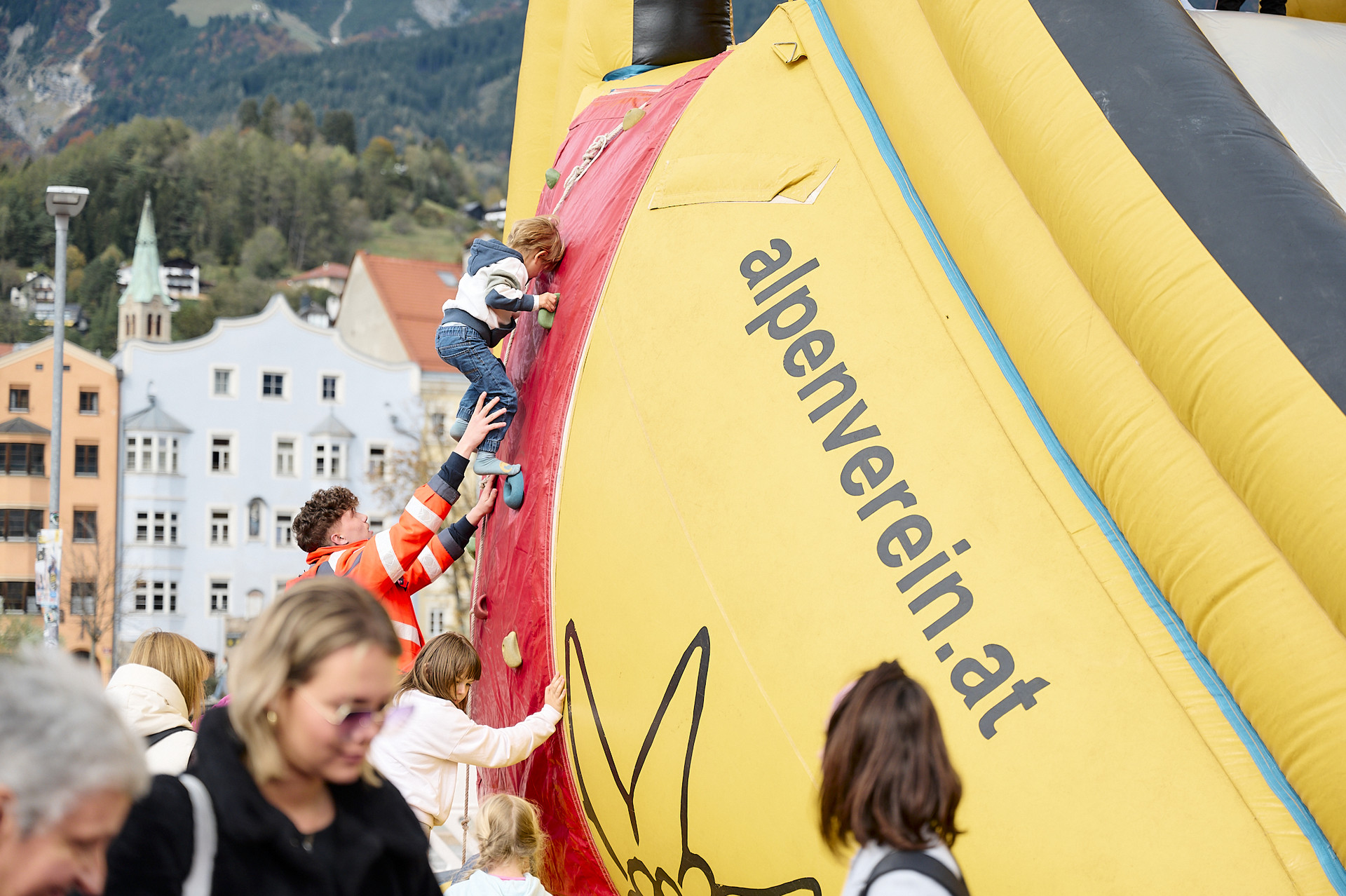 Ein kleines Kind klettert auf die große Rutsche.