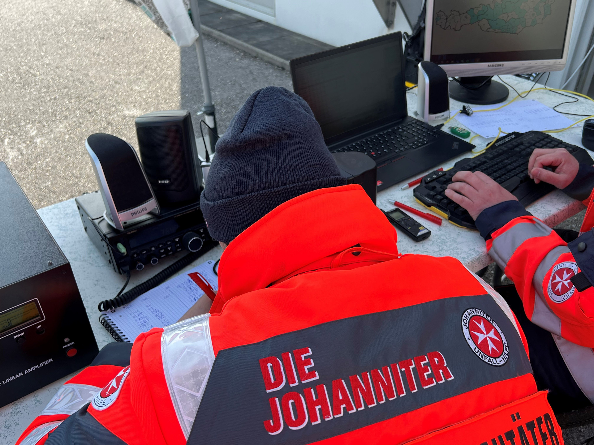 Zwei Personen in Einsatzjacke sitzen vor einem Computer und tragen Resultate in eine Österreichkarte ein.