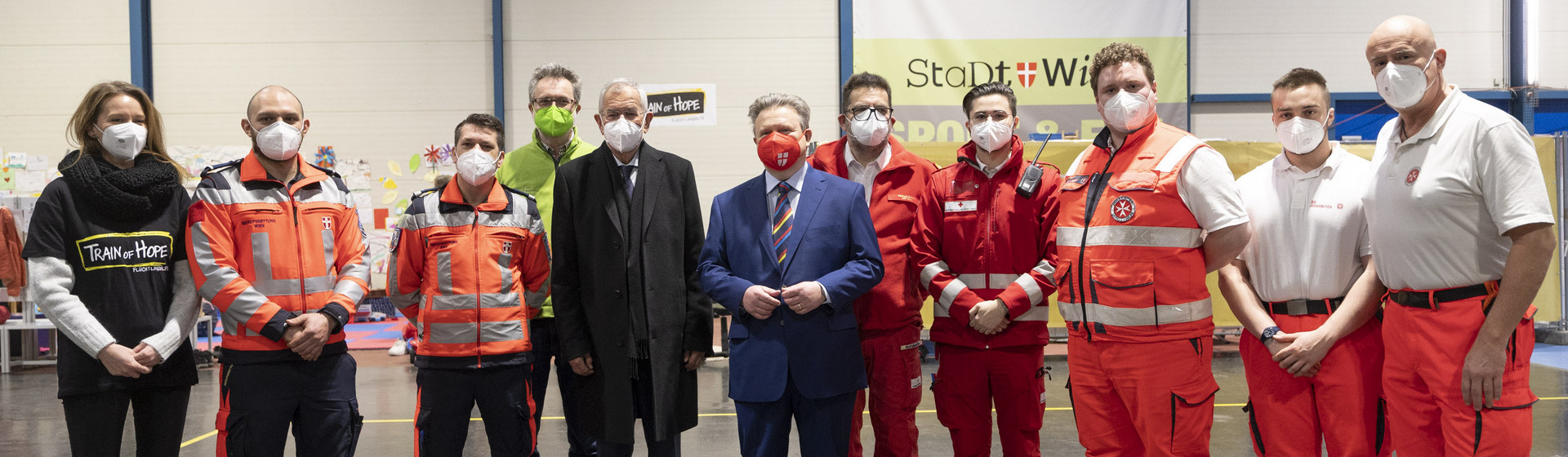 Bundespräsident Van der Bellen und Bürgermeister Ludwig mit Mitarbeiter:innen von Train of Hope, den Johannitern und dem Roten Kreuz.