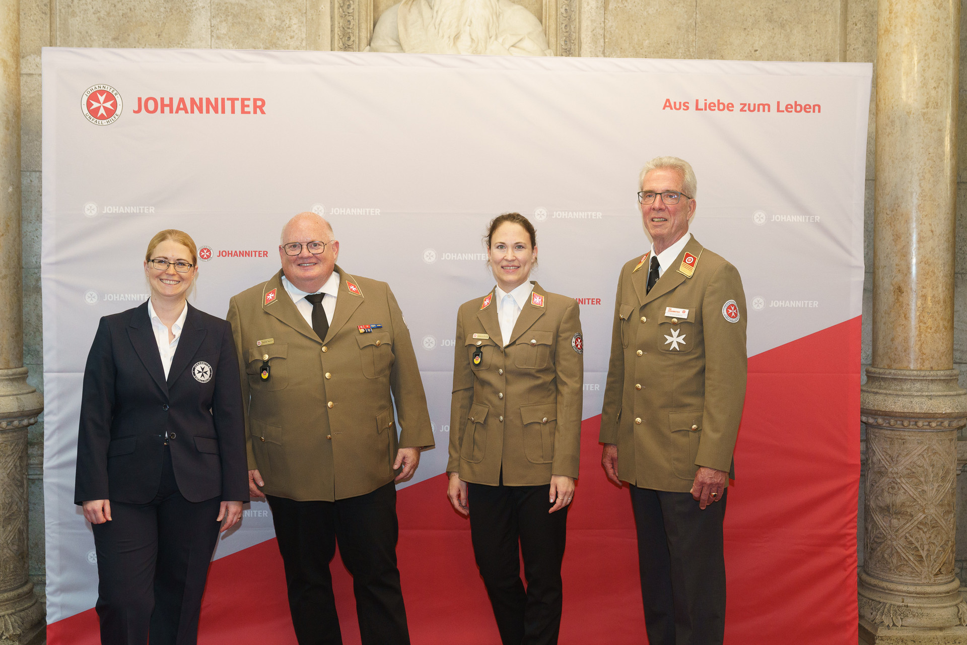Präsident Johannes Bucher und Bundesgeschäftsführerin Petra Grell-Kunzinger mit Personen vor einer Johanniter Leinwand