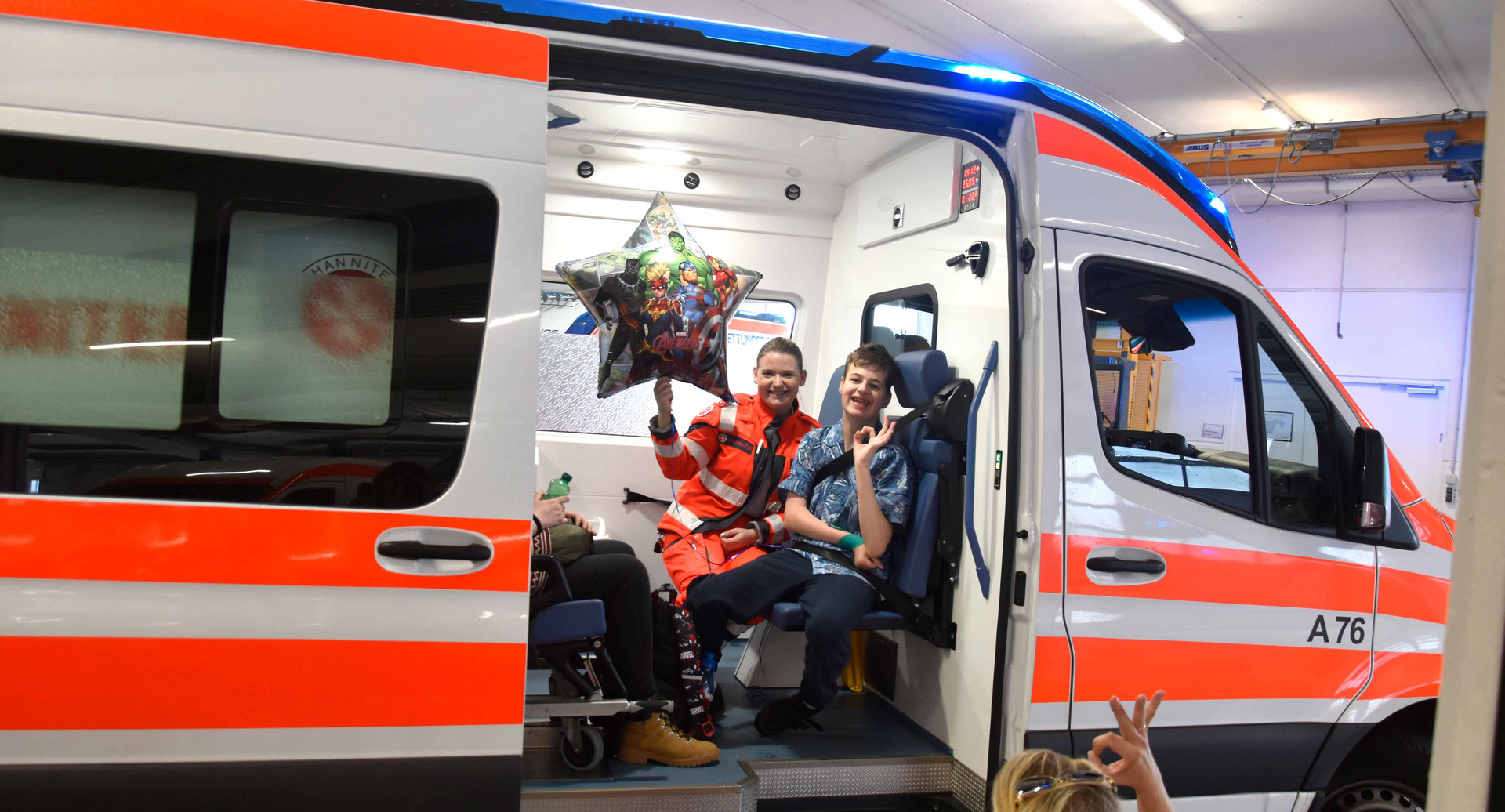 Ein Junge und eine Johanniterin sitzen nebeneinander im Rettungsauto.