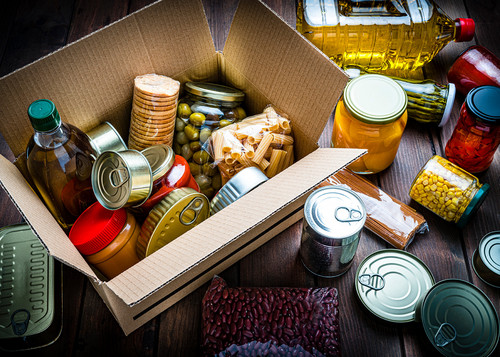 Ein Karton mit lange haltbarem Essen: zum Beispiel Dosen, eingelegtem Gemüse, Nudeln und Öl