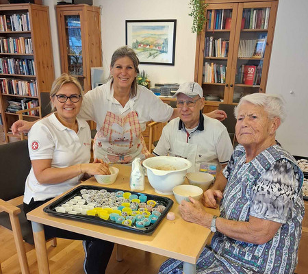 4 Personen sitzen am Tisch beim Kekse backen.