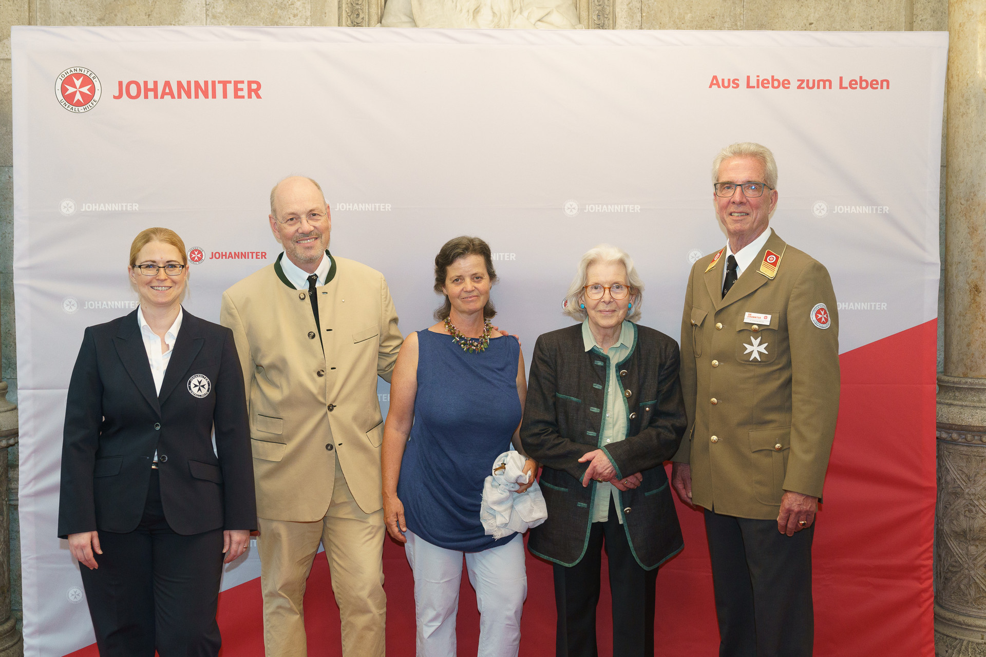 Präsident Johannes Bucher und Bundesgeschäftsführerin Petra Grell-Kunzinger mit Personen vor einer Johanniter Leinwand