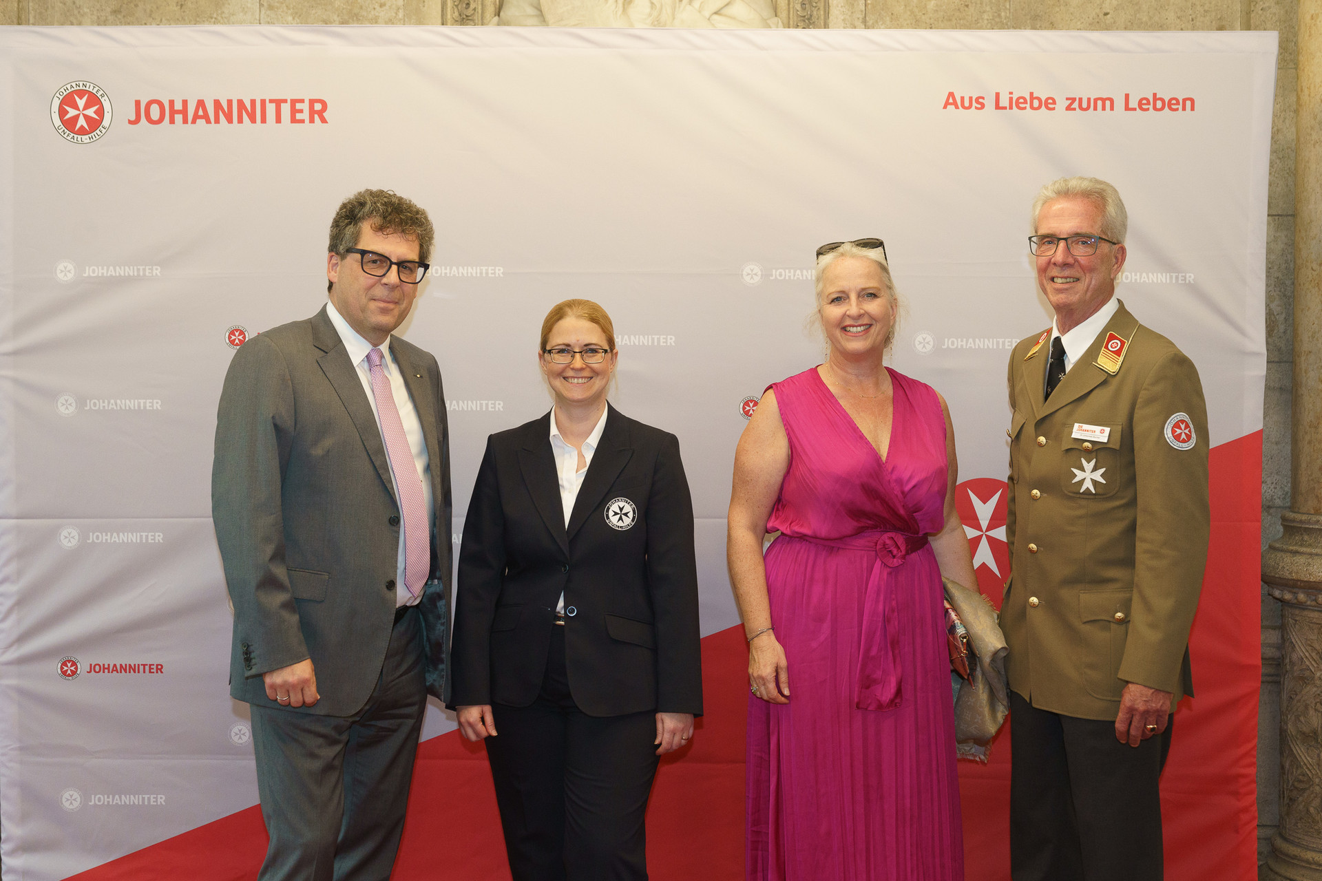 Präsident Johannes Bucher und Bundesgeschäftsführerin Petra Grell-Kunzinger mit Personen vor einer Johanniter Leinwand