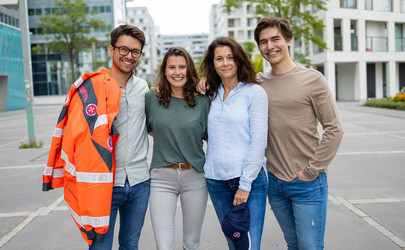 Vier Ehrenamtliche stehen Arm in Arm nebeneinander. Einer davon trägt eine Einsatzjacke des Rettungsdienstes.