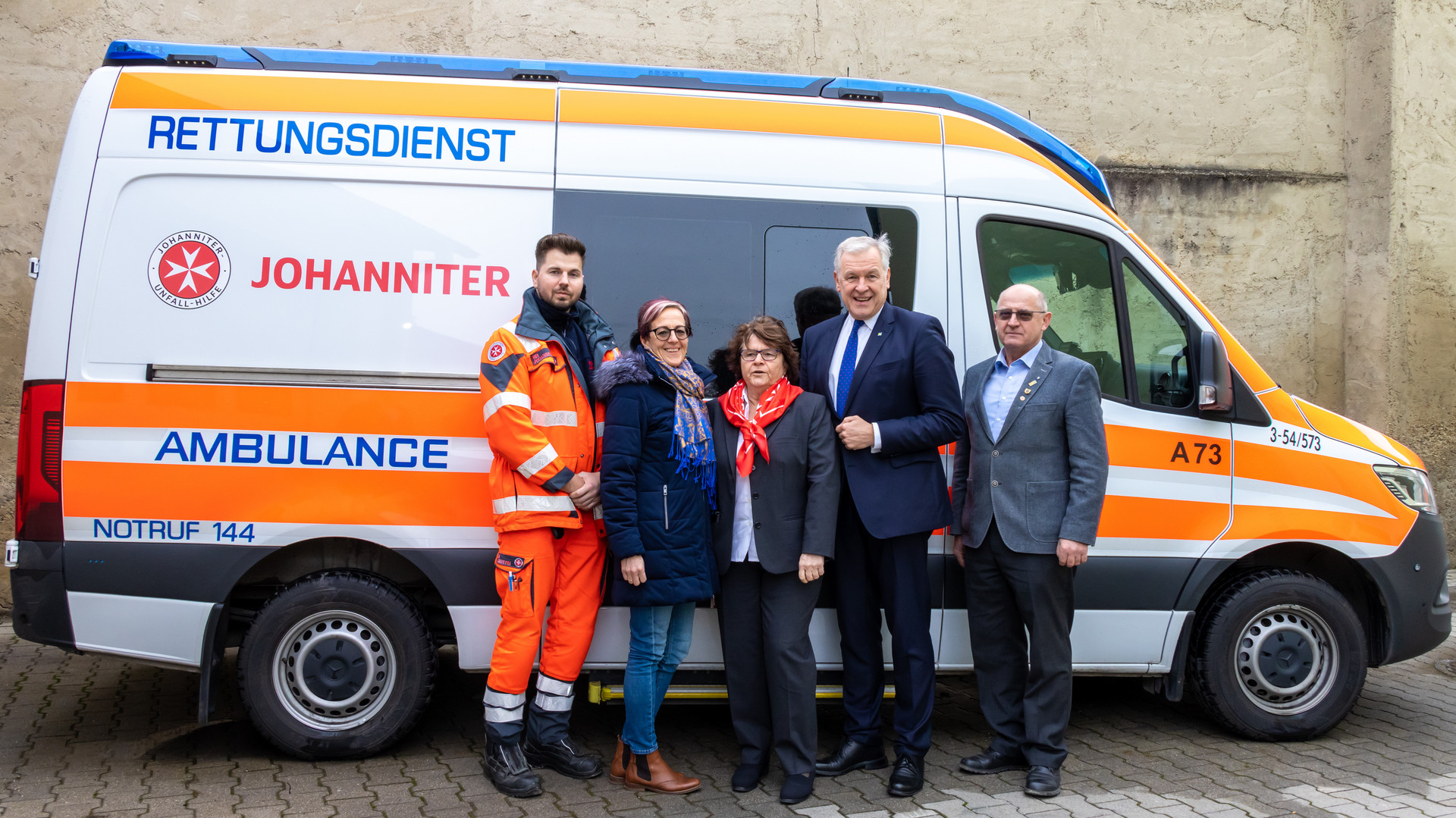 vier Personen posieren vor einem Rettungsfahrzeug für ein Gruppenfoto
