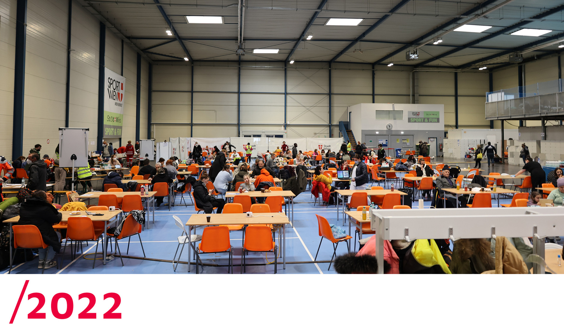 2022: Viele Tische wurden in der Mitte der Sport & Fun Halle aufgestellt, wo ankommende Menschen zur Ruhe kommen können.