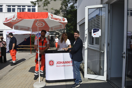 Der Empfang zum Bewerbungstag stehen Johanniter:innen unter einem Sonnenschirm.